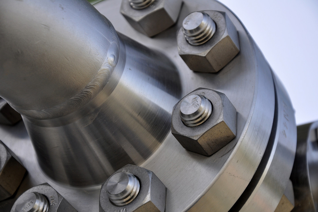 Nahaufnahme einer großen Metallverschraubung mit mehreren massiven Sechskantschrauben.