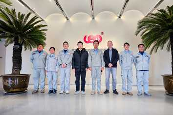 Mehrere Personen stehen in einer offenen Eingangshalle mit Glasfront und Palmen.