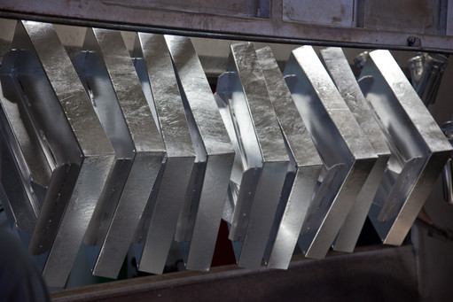 Metallteile nach dem Feuerverzinken hängen nebeneinander in einer Verzinkungsanlage