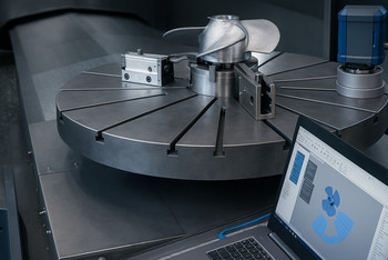 Zwei Männer und eine Frau stehen in einer modernen Fertigungshalle an einer CNC-Maschine mit großem Rundtisch, auf dem ein metallischer Propellerrohling eingespannt ist; rechts daneben ist ein blauer 3D-Laserscanner montiert, während im Vordergrund ein Laptop mit CAD-Modell des Propellers zu sehen ist