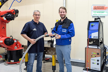 Ein Mann von der SUT und ein Mann von der SLV Halle GmbH halten ein Laserhandschweißgerät in den Händen