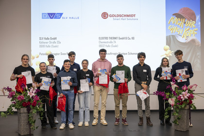 Eine Gruppe junger Menschen hält stolz ihre Urkunden und Geschenke auf einer Bühne mit SLV Halle-Logo. Hinter ihnen werden die Sponsoren und Veranstaltungspartner auf einer Leinwand angezeigt.