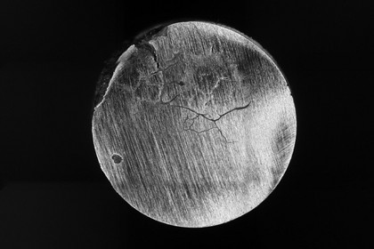 Schwarz-weißes Rasterelektronenmikroskop-Bild eines runden Bruchflächenquerschnitts mit sichtbaren Rissen und Materialstruktur; Maßstabsangabe unten rechts: 23,93 µm.