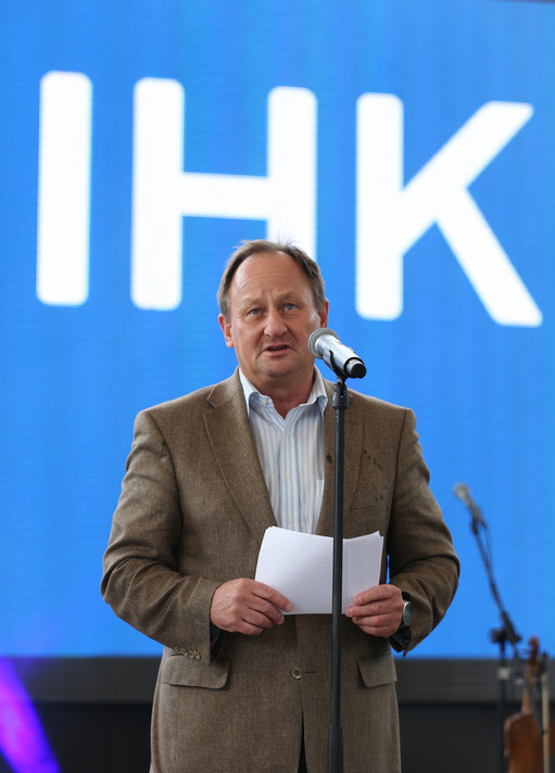 Mann im braunen Sakko spricht auf einer Bühne vor Mikrofon, hält ein Blatt Papier in der Hand, im Hintergrund große blaue Leinwand mit IHK-Schriftzug