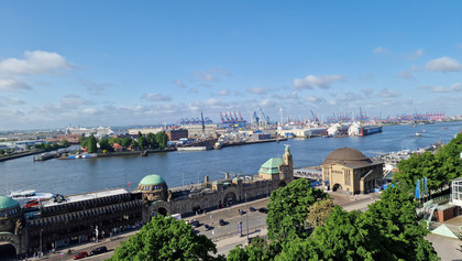 Panoramablick auf den Hamburger Hafen mit den St. Pauli Landungsbrücken im Vordergrund, zahlreichen Kränen und Schiffen im Hintergrund bei klarem Wetter