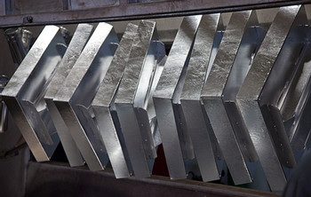 Mehrere silbern glänzende Metallteile hängen nebeneinander nach dem Feuerverzinken.