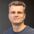 Steffen Wagner, im grauen Shirt, lächelnd vor neutralem Hintergrund