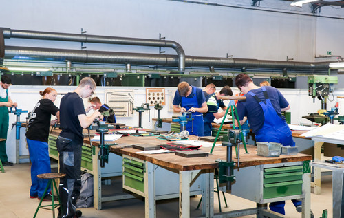 Auszubildende arbeiten konzentriert an Werkbänken in einer Werkstatt