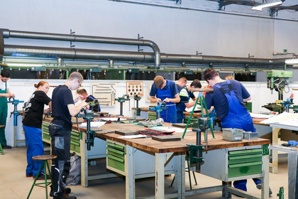 Auszubildende arbeiten konzentriert an Werkbänken in einer Werkstatt