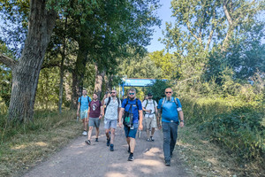 6 Männer wandern lächelnd durch Natur