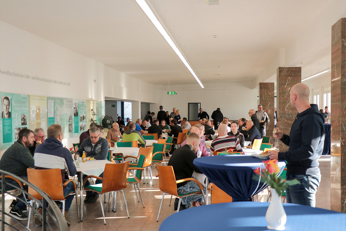 Teilnehmende bei einer Mittagspause in einem sonnendurchfluteten Foyer 