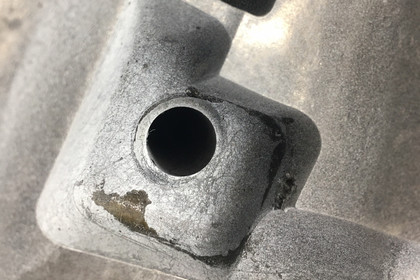 Nahaufnahme eines Metallbauteils, zeigt eine runde Bohrung und leichte Gebrauchsspuren auf der Oberfläche.