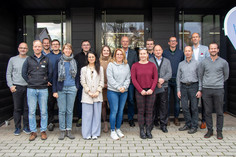 Gruppenfoto vor einem Eingangsbereich mit zwei DVS SLV Halle-Bannern, die Personen stehen auf einem gepflasterten Vorplatz und blicken freundlich in die Kamera.