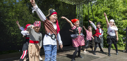 Sieben Kinder in Piratenkostümen tanzen auf einer Freilichtbühne