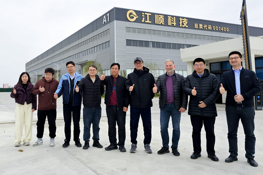 Gruppe von Personen steht im Freien vor einem Gebäude und posiert gemeinsam für ein Gruppenfoto bei Tageslicht.