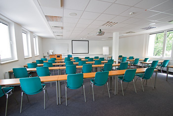 Raum mit Fensterreihen rechts und links, Rednerpult, Whiteboard, Beamer und Flipchart