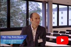 Ein Mann mit Anzug sitzt in einerm Seminarraum, unten links ist der Name "Dipl.-Ing. Sven Nocack" und darunter "Leiter der Betriebsstätte Dresden der SLV Halle" eingeblendet, rechts unten befindet sich das YouTube Icon