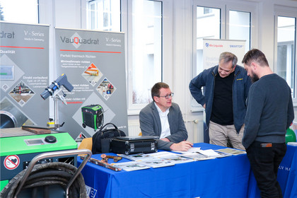 Beratungsgespräch an einem Informationsstand im Rahmen der 33. Erfahrungsaustausch-Weiterbildung für Schweißaufsichtspersonen. Technische Produkte und Fachinformationen werden präsentiert.