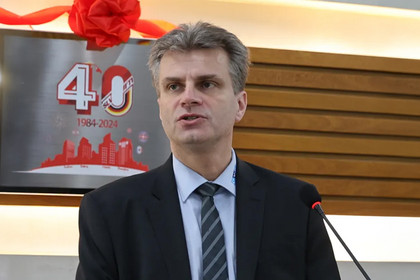 Nahaufnahme eines Redners, der während einer Feier eine Ansprache hält. Im Hintergrund ist das Logo der 40-Jahr-Feier sichtbar.