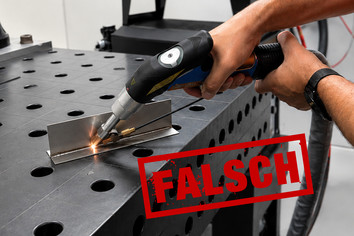 Eine Person führt Schweißarbeiten an einem Metallbauteil auf einer Werkbank aus. Im Vordergrund ist der rote Schriftzug „FALSCH“ zu sehen, die Person trägt keine erkennbaren Schutzhandschuhe.