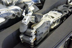 Nahaufnahme einer metallischen Roboterhand mit beweglichen Fingergelenken, schwarzen Gehäuseteilen und sichtbaren Schraubverbindungen, die in einer Schaumstoffaussparung liegt.