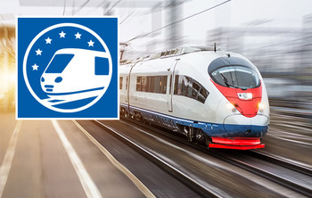 Ein weißer Fernzug mit roter Front fährt mit hoher Geschwindigkeit durch einen Bahnhof, umgeben von moderner Architektur und Lichtspuren.