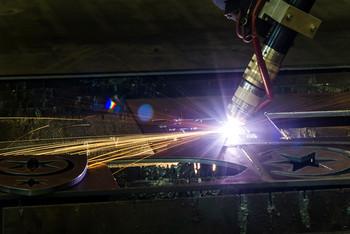 Schweißbrenner erzeugt einen grellen Lichtbogen auf einer Metalloberfläche, Funken sprühen nach außen.
