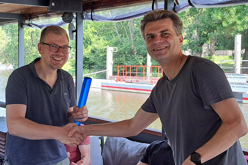 Steffen Wagner reicht symbolisch einen Gegenstand an Dr. Florian Otto Schumann weiter. 