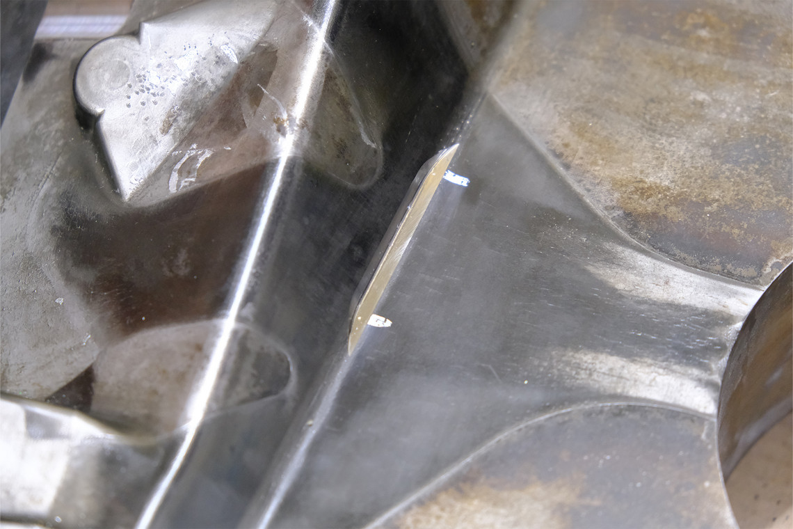 Metallisches Werkstück mit erkennbarer Vertiefung und glatter Schweißnahtstelle.